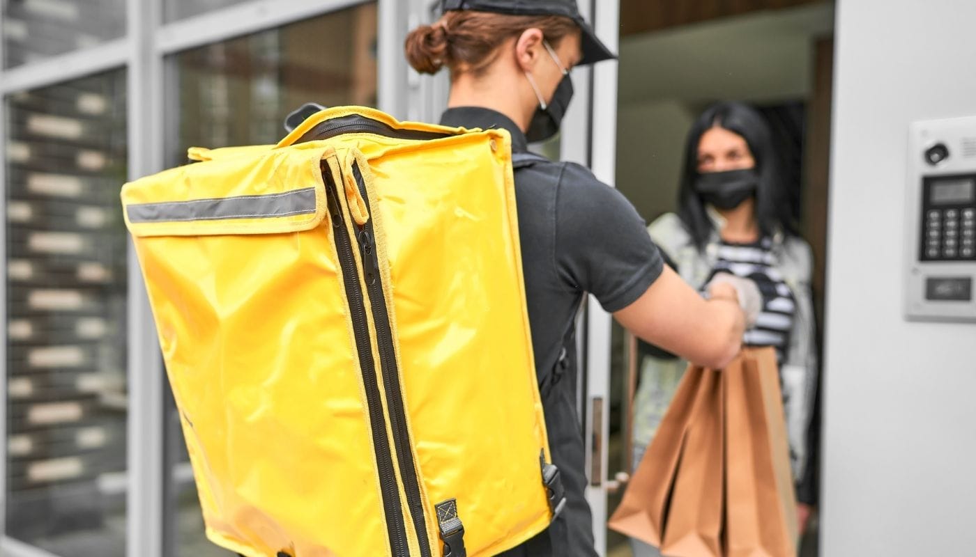 Um mensageiro com uma mochila e comida entregou um pedido de um fornecedor de produtos para revenda na casa do cliente