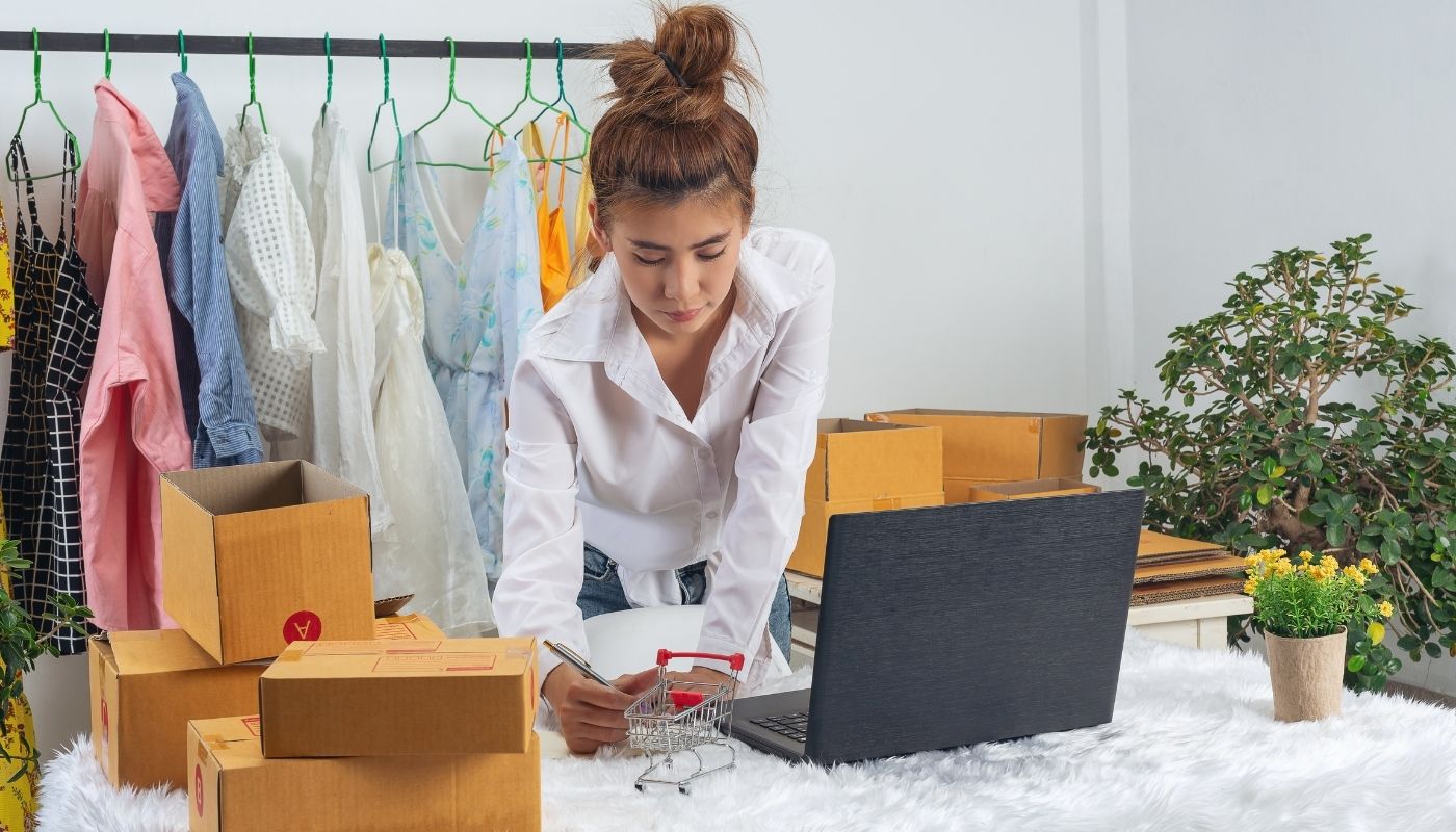 mulher catalogando itens de vestimentas, um dos requisitos do guia sobre como montar loja virtual de roupas